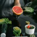 Person preparing a healthy meal with fresh grapefruit, kiwi, and lettuce.